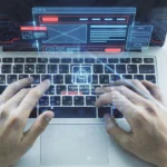 A person's hands typing on a laptop keyboard, with a holographic overlay of an AI landing page generator interface showing a website wireframe and a progress bar.